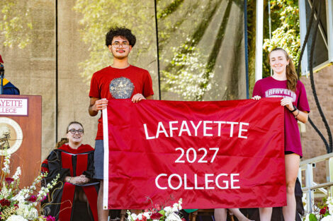 Two students stand with a Lafayette College 2027 flag.