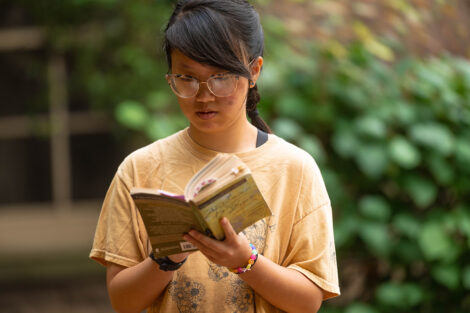 A student opens a book, reading.