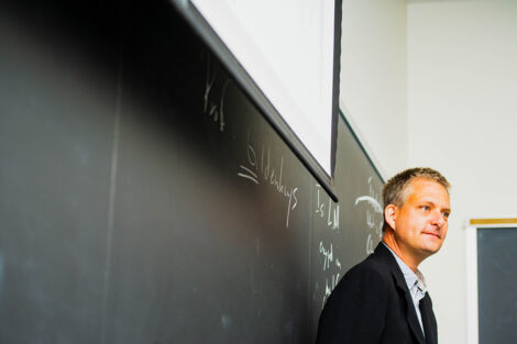 A professor teaches in front of a blackboard.