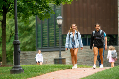 Students walk across a brick path in front of Skillman Library.