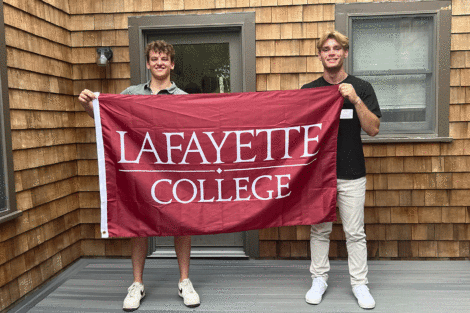 Two students smile at the camera and hold a Lafayette flag