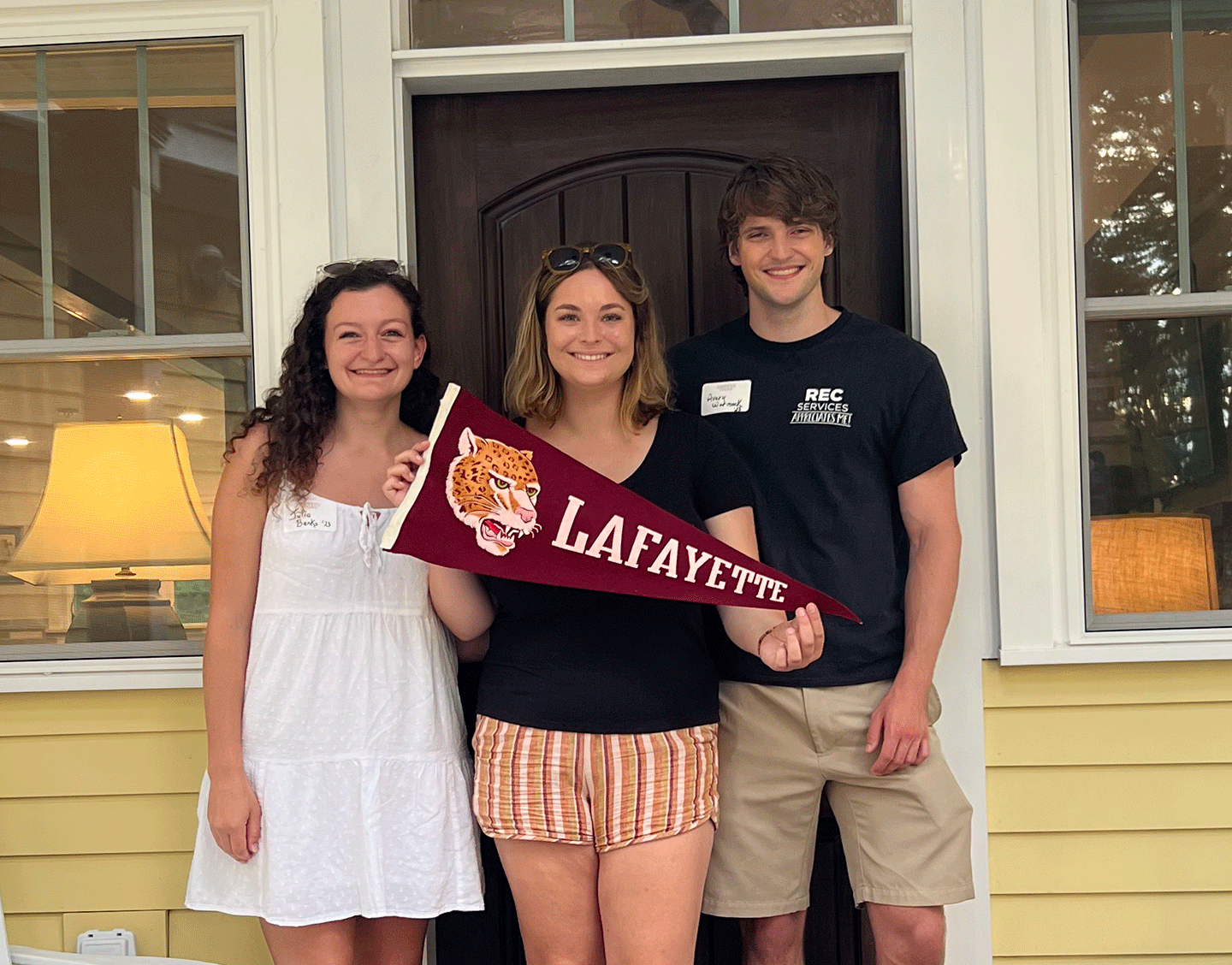 Three students smile at the camera and hold a Lafayette flag