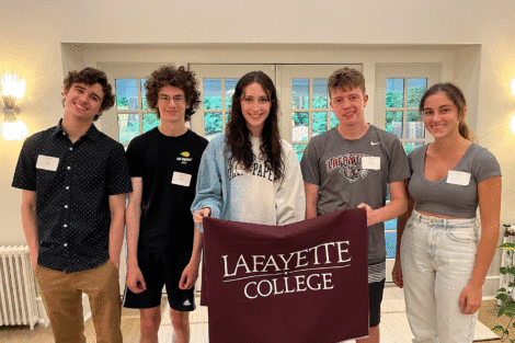 Incoming students smile at the camera and hold a Lafayette flag