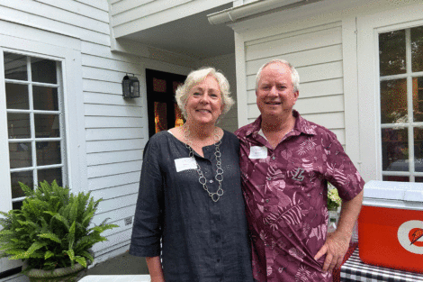Jenny and Michael Weisburger are standing arm in arm outside and are smiling at the camera
