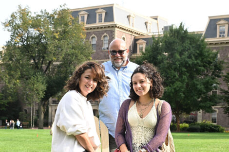 A mom and dad pose with their daughter on the Quad.