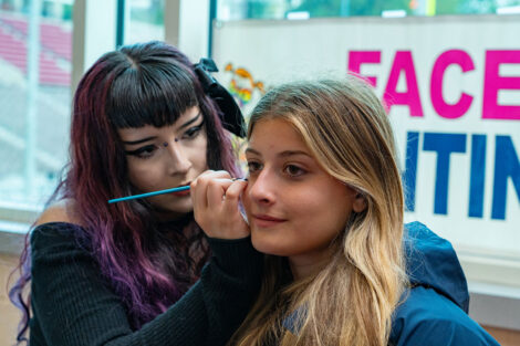A student is getting her face painted by an artist.