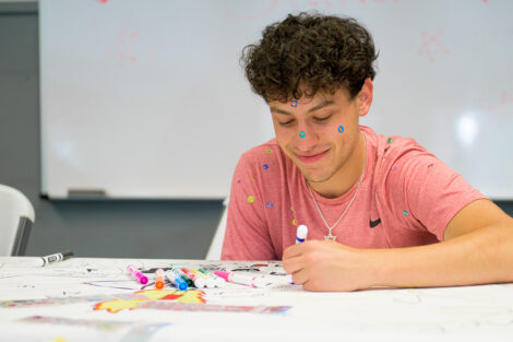 A Lafayette student, covered in stickers, draws.