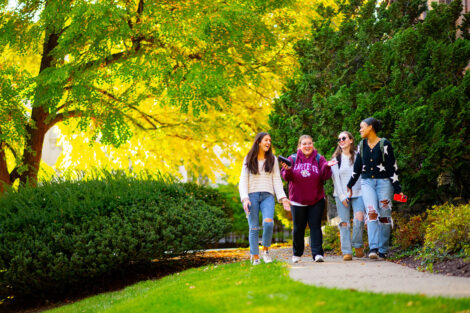 Students talk while walking along a campus path.