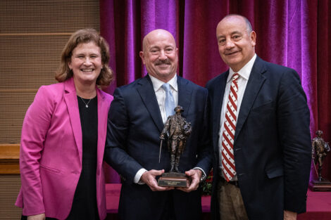 President Nicole Farmer Hurd, Angel Mendez '82, and Chair of the Board of Trustees Robert Sell '84 stand and smile at the camera. Angel Mendez is holding a statue of the Marquis.