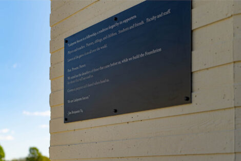 A gray plaque on the outside of Gummeson Grounds has a message for all those who enter the stadium.