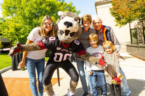 A family poses with the Leopard mascot at Homecoming.