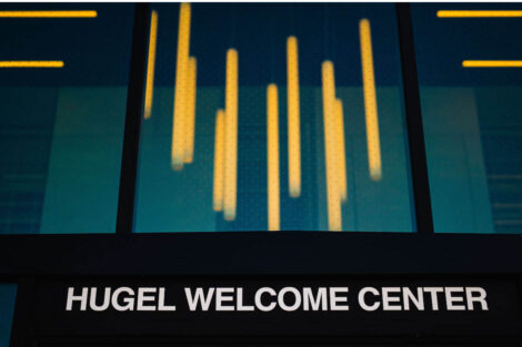 Overhead lights illuminate the name Hugel Welcome Center from the outside of the building.