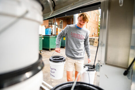Pierson White '24 lifts composting buckets.