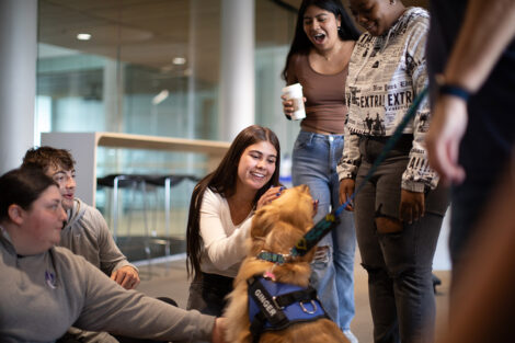A student smiles at a dog.