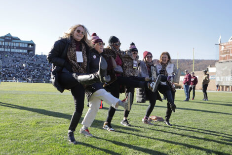 Staff members, including President Nicole Hurd, practice kicking in a line.