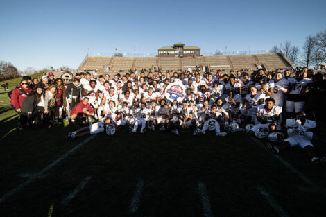 Football players on the field pose for a picture.