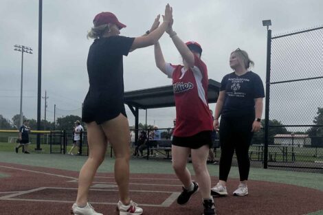 A Lafayette student high fives a Miracle League athlete on the field.