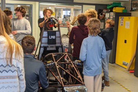A Lafayette student stands behind a car chassis and talks with Nazareth Middle School students.