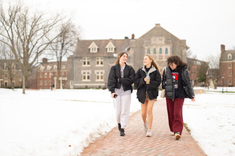 A group of students walk along a campus path.