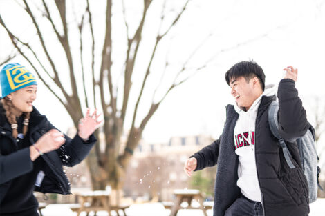 Two students have a snowball fight.