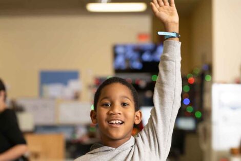 An elementary-aged child raises his hand.