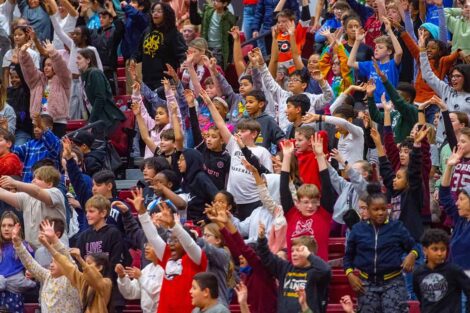 Students stand up with arms outstretched for a tshirt toss during School Day Game
