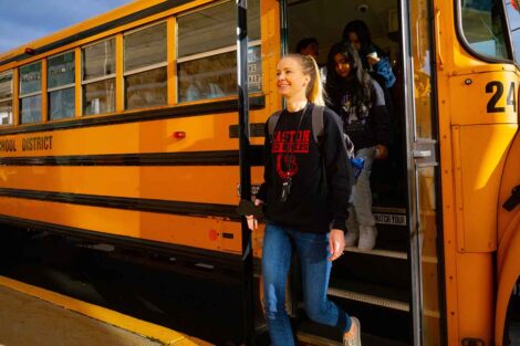A teacher leaves the school bus with her class en route to the School Day game.