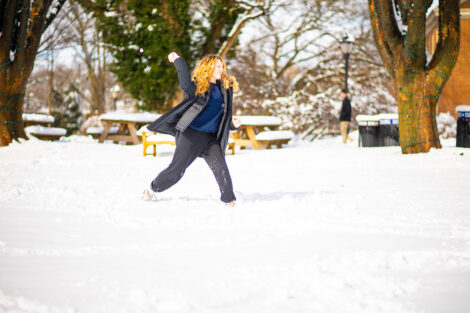 A student is featured on the Quad throwing a snowball.