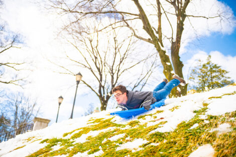 A student sleds down a hill on campus.