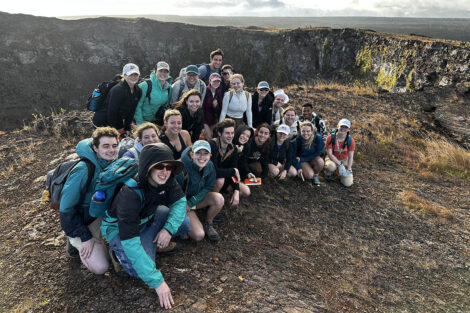Students smile in front of scenic view in Hawaii.