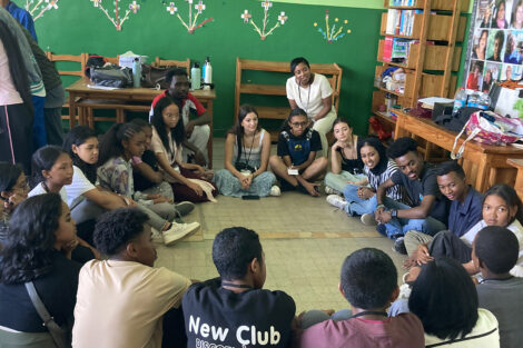 Students talk to other students in a circle on the floor.