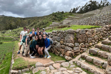 Students smile in front of scenic landscape in Peru.