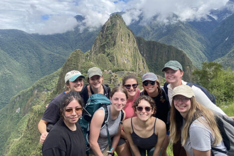 Students smile in front of scenic landscape in Peru.