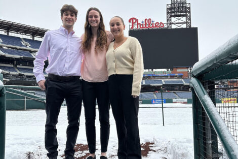 Courtney Campbell ’25, Jeremy Frankel ’24, Anna Gonella ’25 pose in front of the Phillies scoreboard