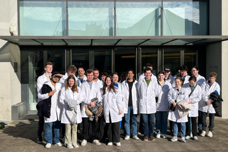 Students wear lab coats outside of a business in Portugal.