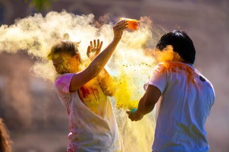 Two students throw colorful powder on each other at the Holi Fest.