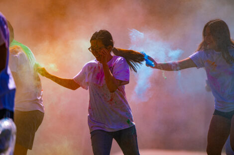 A student is featured in a fog of colorful powder form the Holi Fest.
