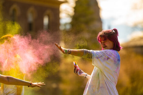A student throws colorful powder at another student.
