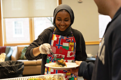 A student serves food at the ISA food tasting event.