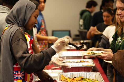 A student serves food at the ISA food tasting event.