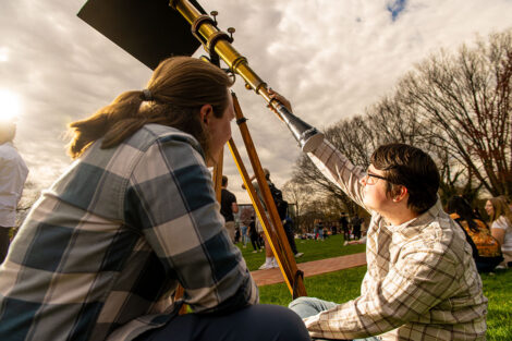 Students use a telescope to look at the scene.