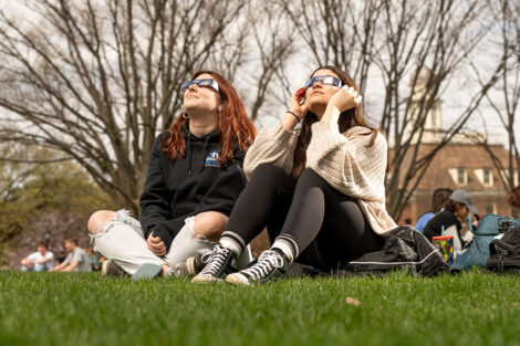 Students wearing solar eclipse glasses watch the solar eclipse.