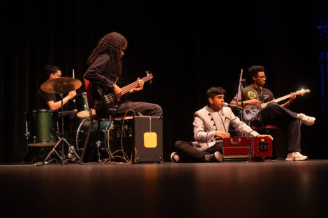 A group of students play instruments on stage.