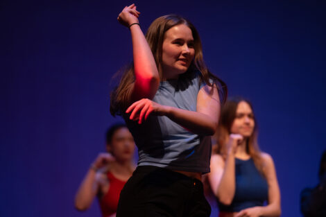 A student is featured prominently among other students during a stage performance.