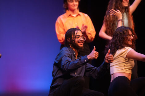 A student gives a thumbs up following an on-stage performance.