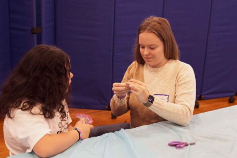 A Laf volunteer helps a student at Paxinosa with a friendship bracelet