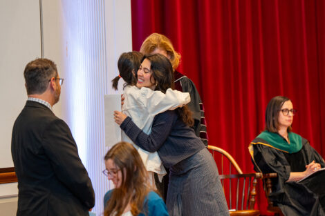 A student hugs their professor on stage at Colton Chapel.