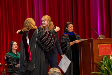A student hugs President Nicole Hurd while accepting an award on stage at Colton Chapel.