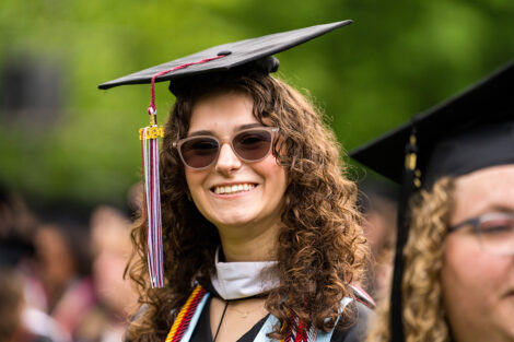 A graduate smiles in the crowd.