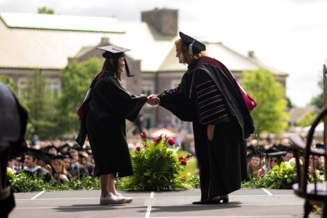 A student shakes hands with President Nicole Hurd.